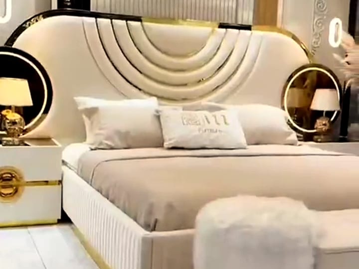 Chambre à coucher exposée chez Yaye Dia Agro : lit capitonné à tête de lit dorée et chevets